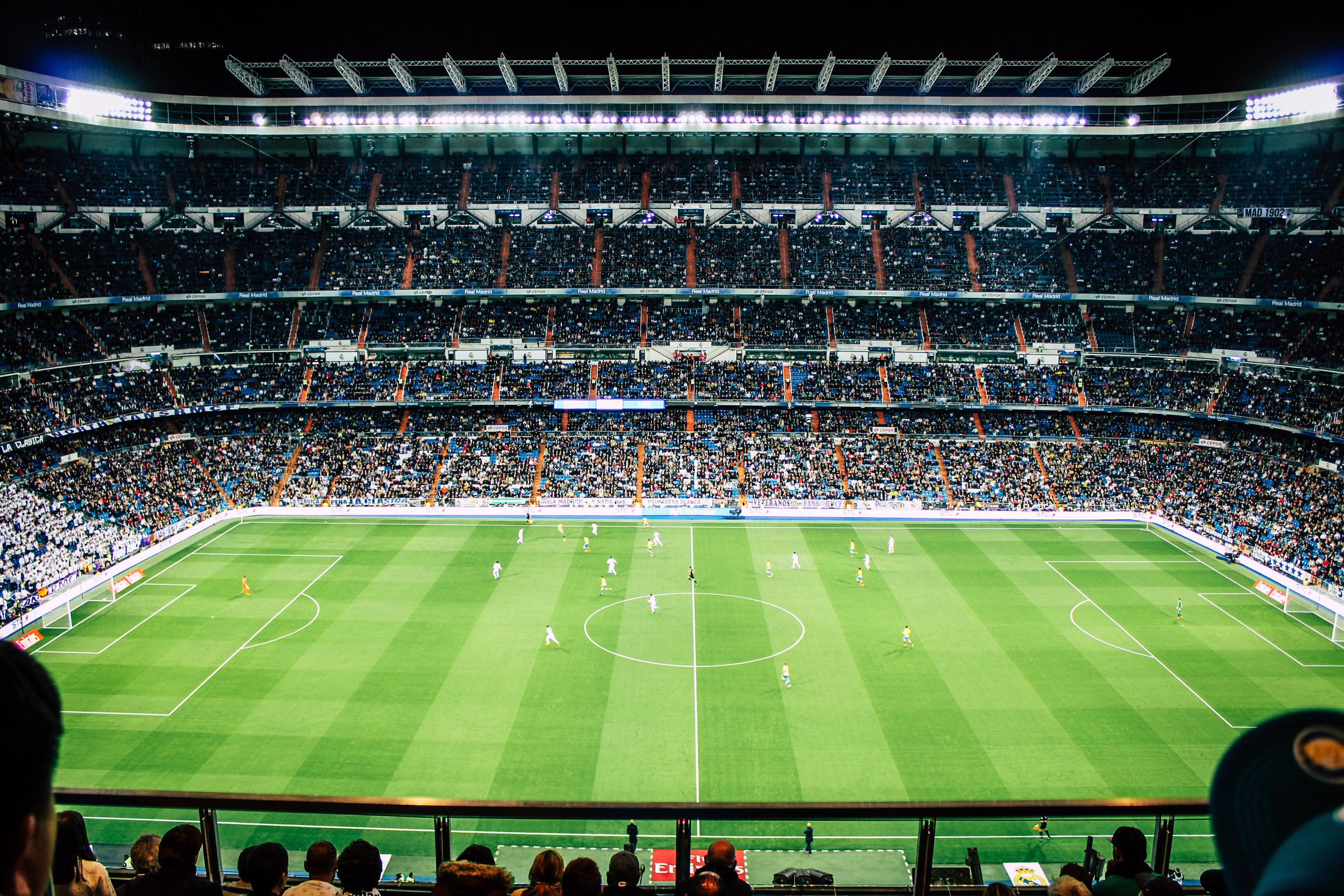 A floodlit soccer pitch seen from the stands.